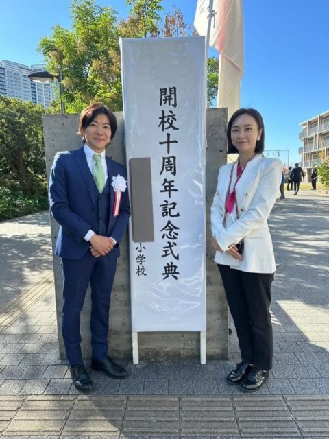 創立10周年記念式典看板前に立つ音喜多と三次ゆりか