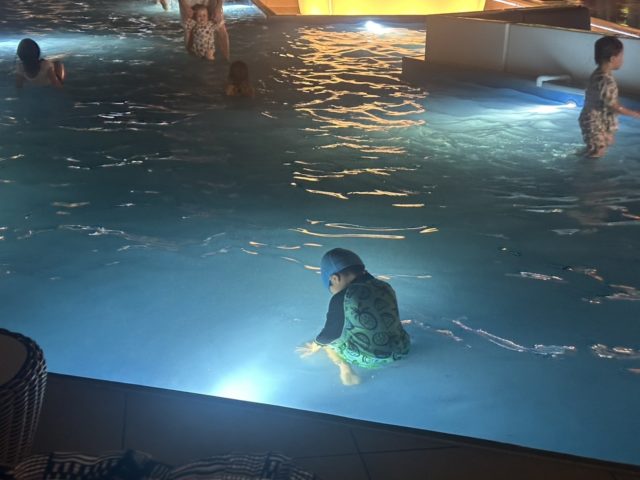 夜のプールで遊ぶ子どもの後ろ姿