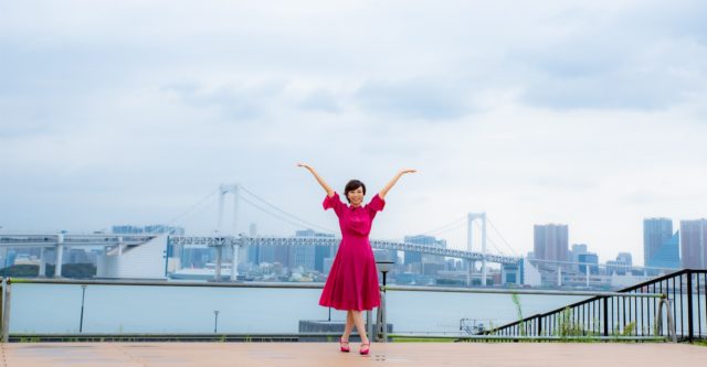 海辺で両手を広げる笑顔の三次ゆりか