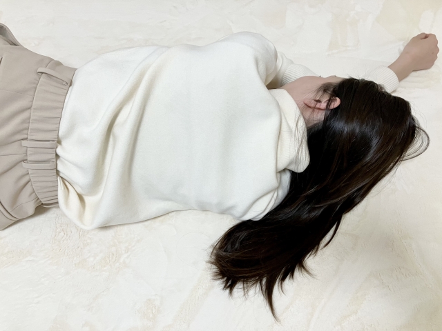 床に倒れ込む女性の後ろ姿